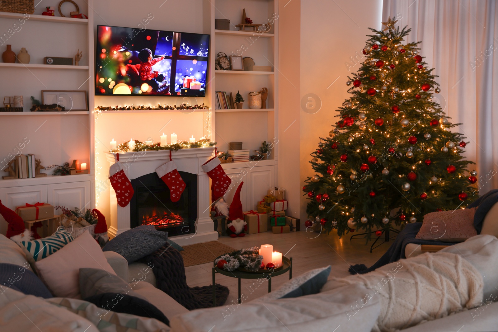 Photo of TV set with Christmas movie above fireplace in cosy room. Winter holidays atmosphere