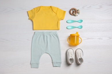 Flat lay composition with baby clothes and accessories on white wooden table