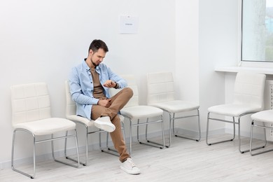 Photo of Man looking at wrist watch and waiting for job interview indoors