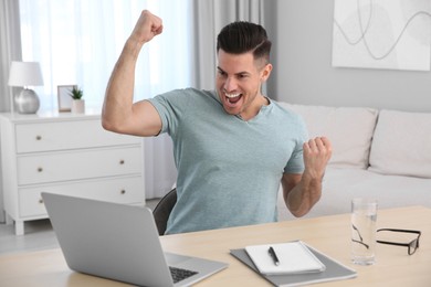 Photo of Emotional man participating in online auction using laptop at home