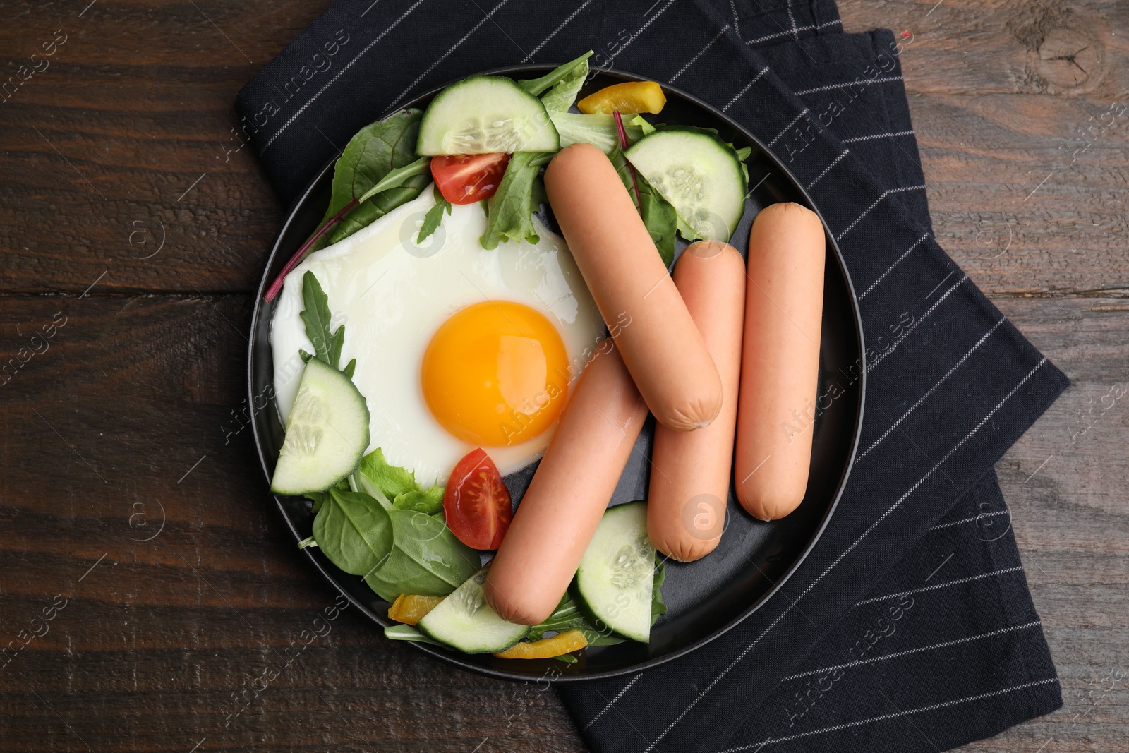 Photo of Delicious breakfast with boiled sausages and fried egg on wooden table, top view