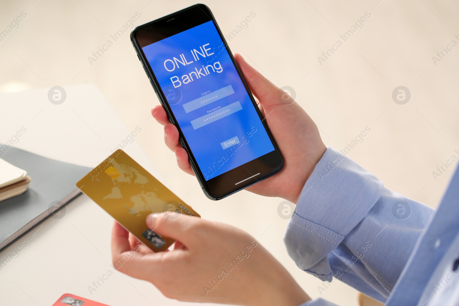 Photo of Woman using online banking app on smartphone and credit card at white office table, closeup