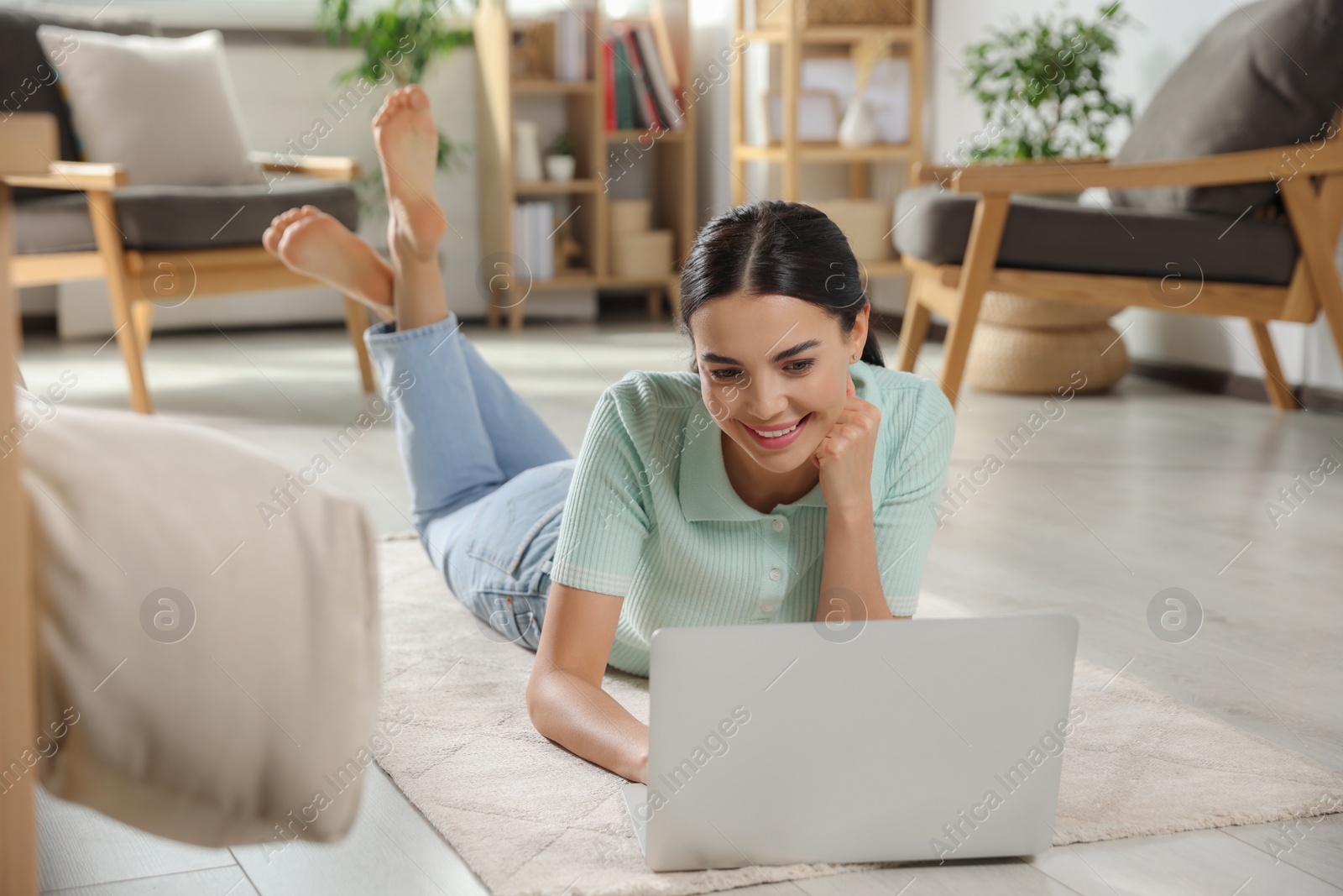 Photo of Young woman working with laptop on floor at home