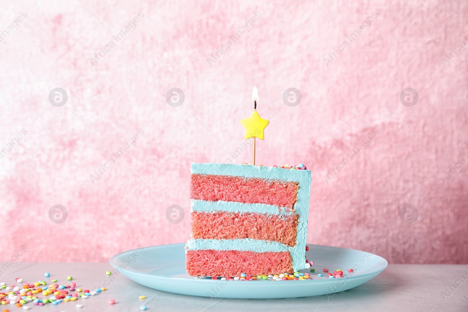 Photo of Slice of fresh delicious birthday cake with candle on table against color background