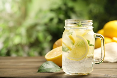 Photo of Mason jar of cold lemonade on wooden table