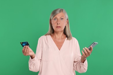 Photo of Worried woman with credit card and smartphone on green background. Be careful - fraud