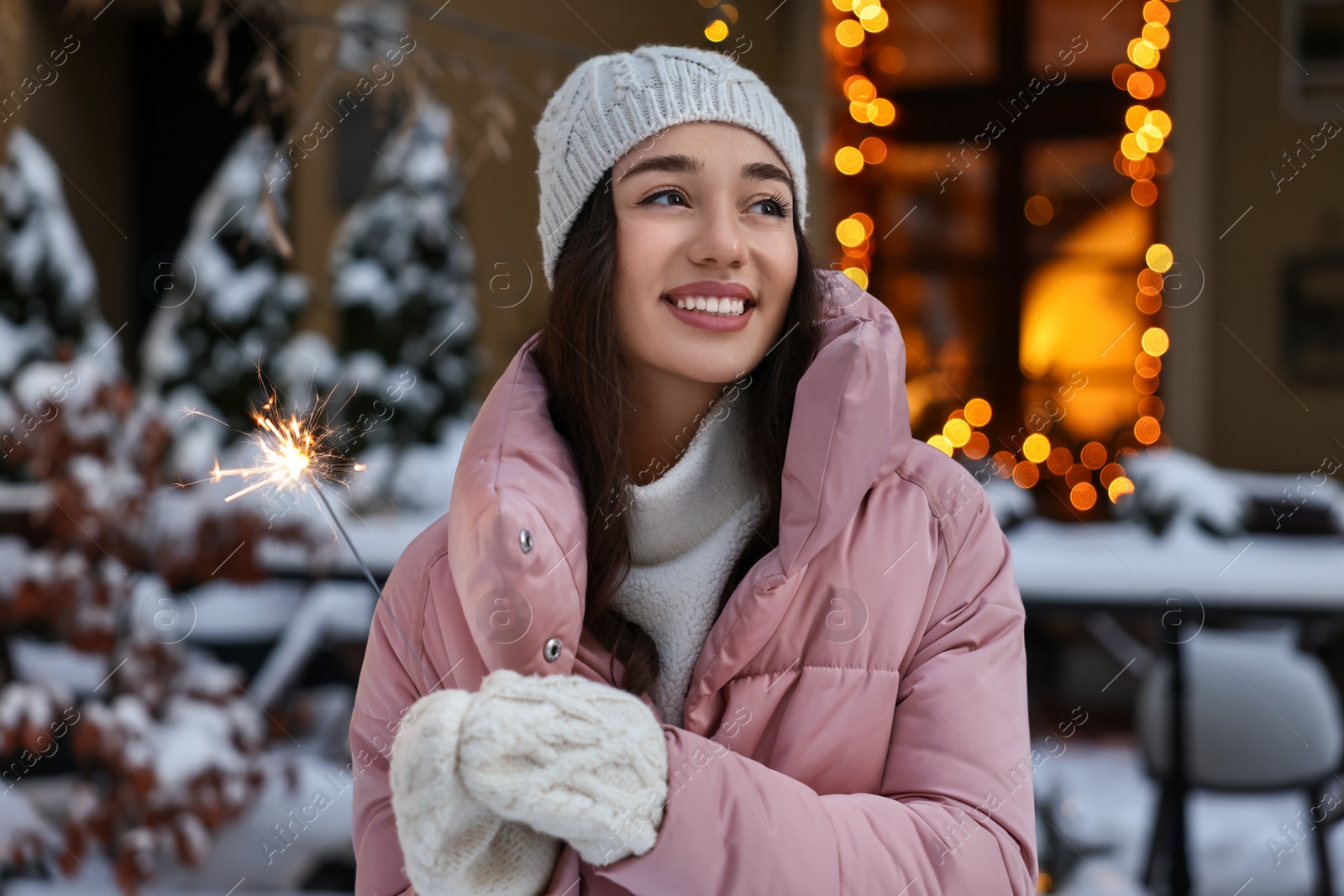 Photo of Portrait of smiling woman with burning sparkle on snowy city street