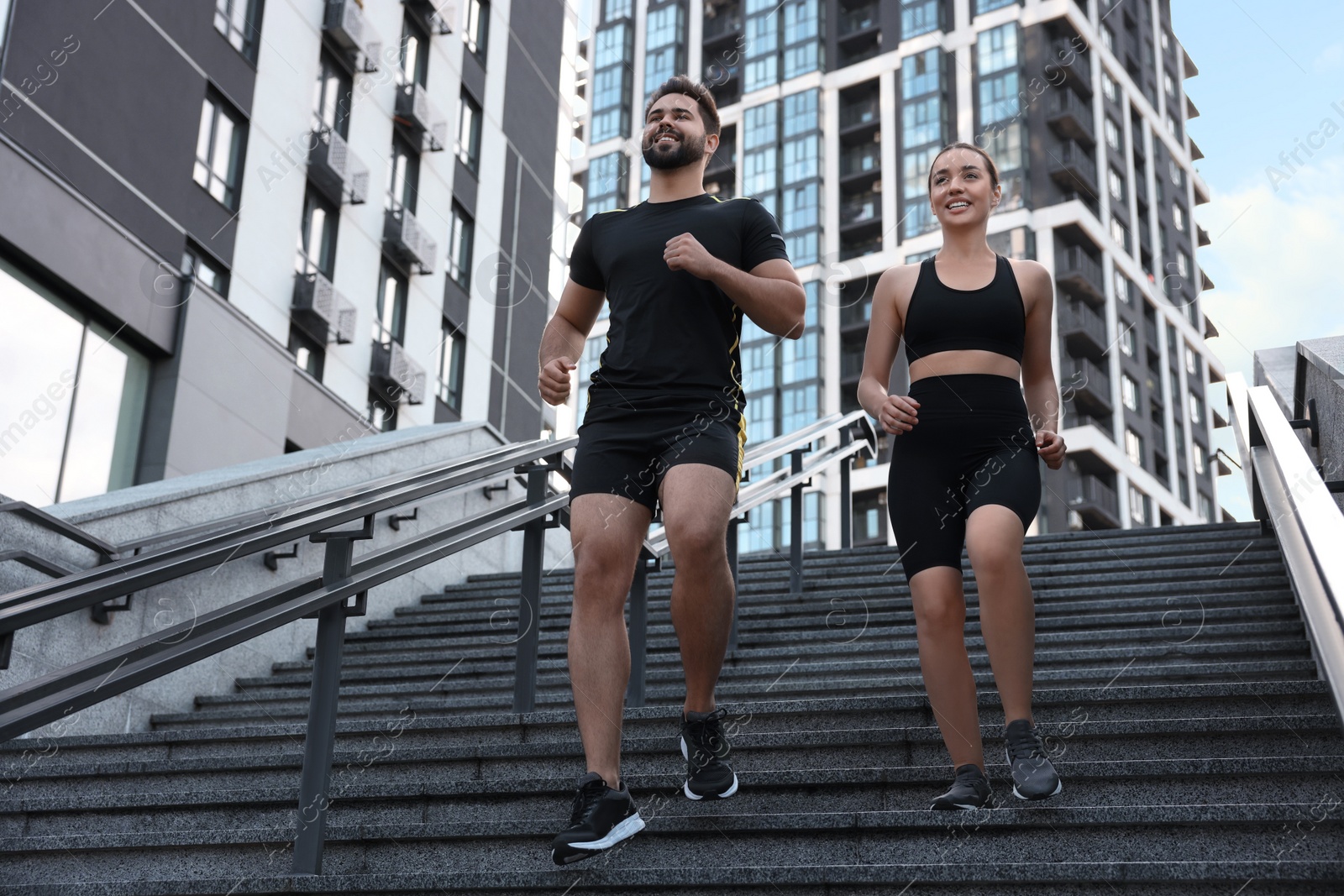 Photo of Healthy lifestyle. Happy couple running on steps outdoors, low angle view