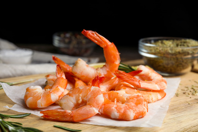 Photo of Delicious cooked shrimps with rosemary on wooden board