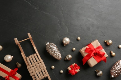 Beautiful Christmas composition with miniature sleigh on black slate table, flat lay. Space for text