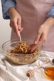 Woman making granola at table in kitchen, closeup