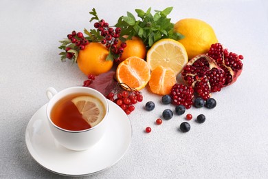 Cup of delicious immunity boosting tea with ingredients on light grey table