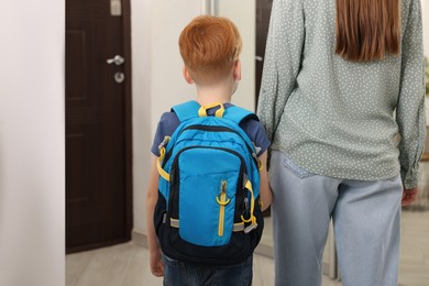 Photo of Young mom taking her son to school, back view