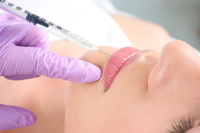 Photo of Young woman getting lip injection in beautician salon, closeup