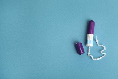 Photo of Tampon with package on turquoise background, flat lay. Space for text