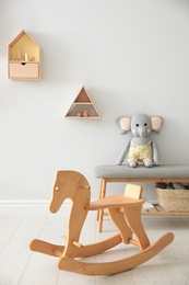 Photo of Wooden rocking horse in cute children's room interior. Stylish design