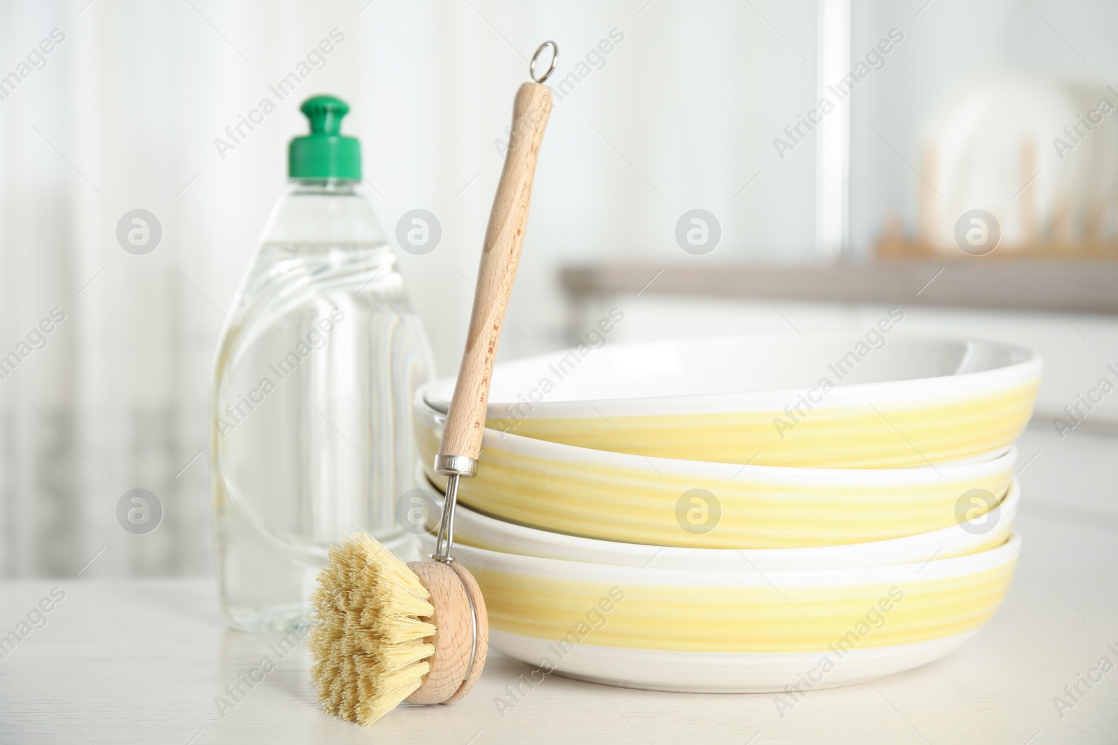 Photo of Cleaning supply and brush for dish washing near bowls on white table indoors