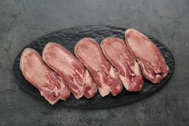 Photo of Raw beef tongue pieces on grey table, top view