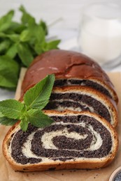 Cut poppy seed roll and mint on parchment paper, closeup. Tasty cake