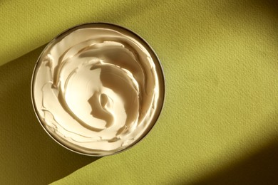 Photo of Jar of face cream on green background, top view. Space for text