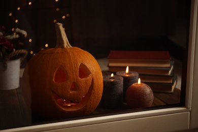 Composition with pumpkin head on windowsill, view through glass. Jack lantern - traditional Halloween decor