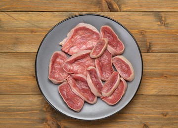 Raw beef tongue pieces on wooden table, top view