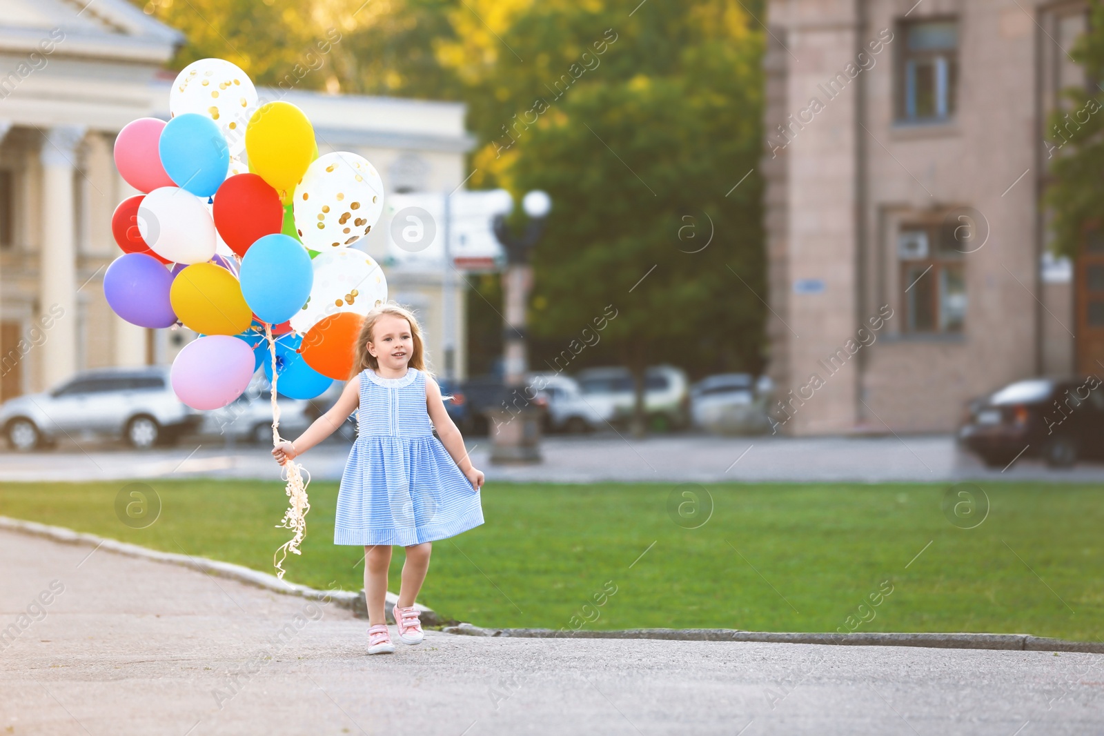 Photo of Little girl with colorful balloons outdoors on sunny day