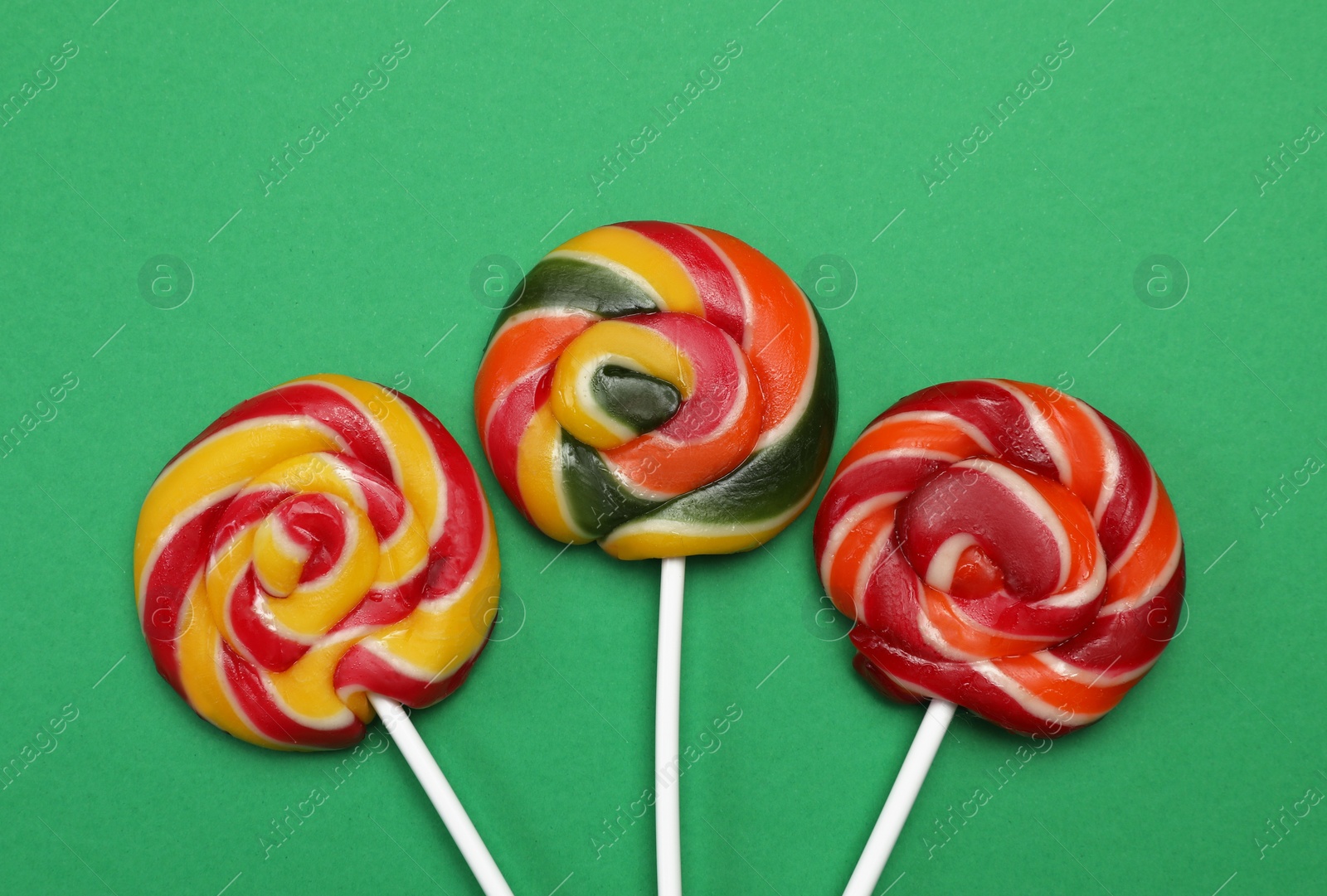 Photo of Sweet lollipops on green background, flat lay