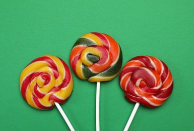 Photo of Sweet lollipops on green background, flat lay