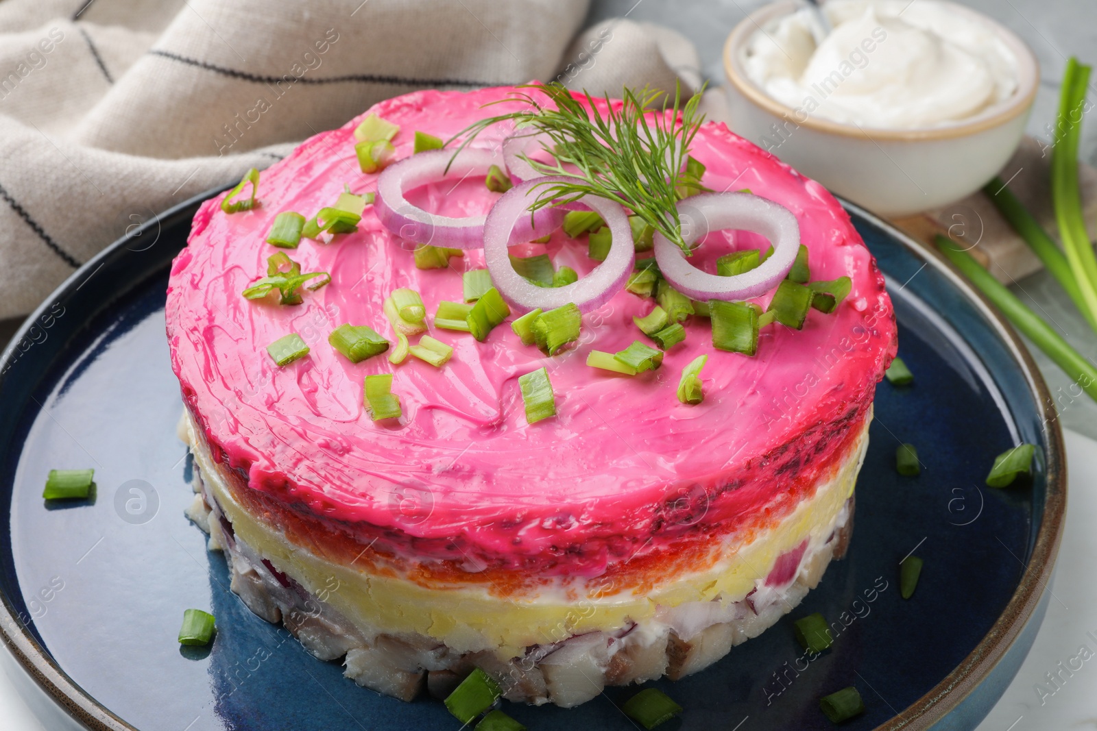 Photo of Herring under fur coat salad on light grey table, closeup. Traditional Russian dish