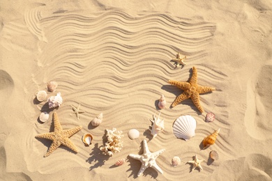 Starfishes and seashells on beach sand with wave pattern, flat lay. Space for text