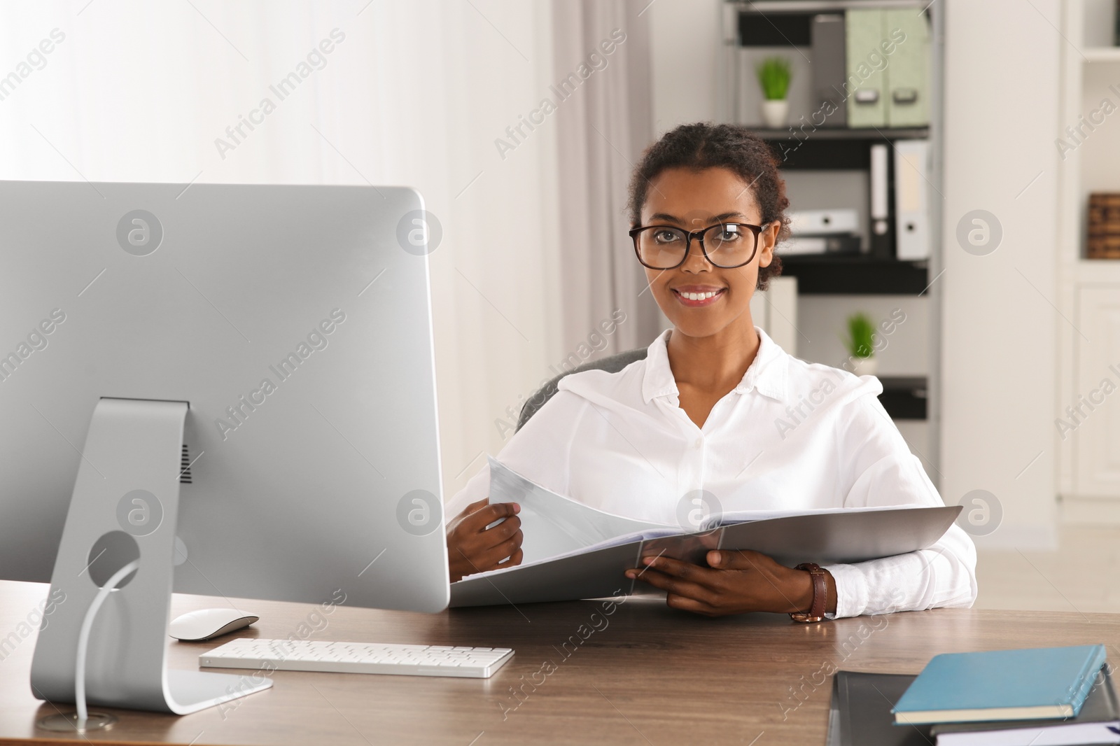 Photo of African American intern with folder working at table in office