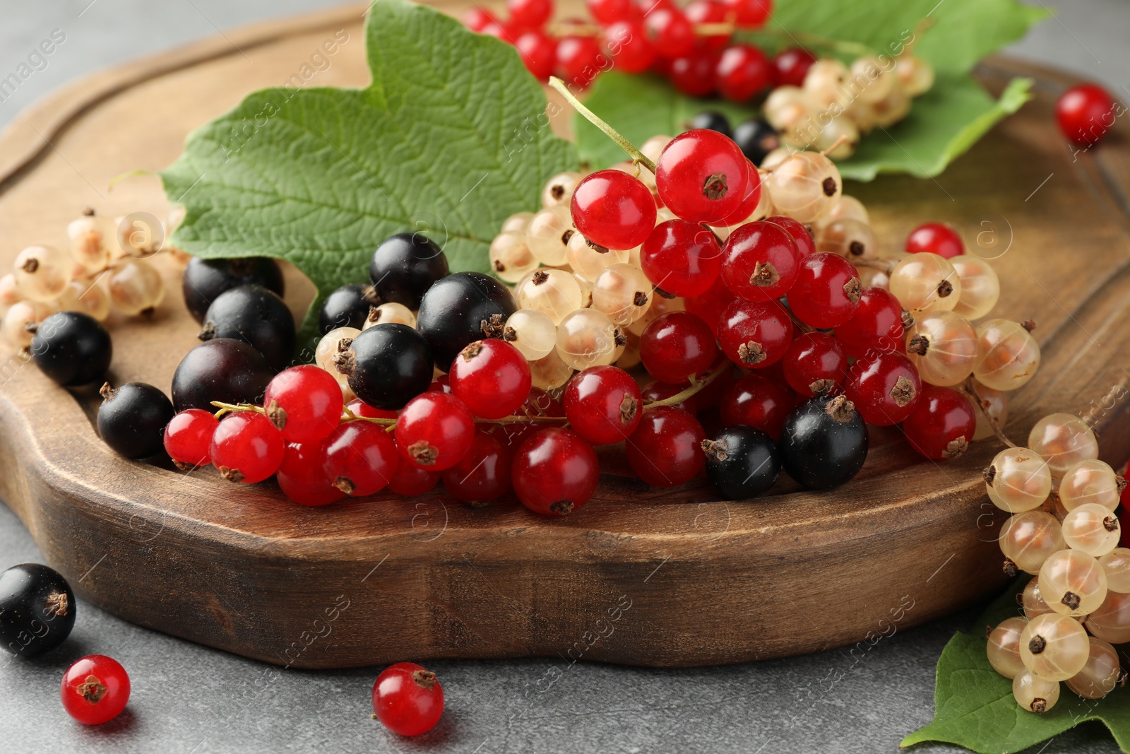 Photo of Different fresh ripe currants and green leaves on table, closeup