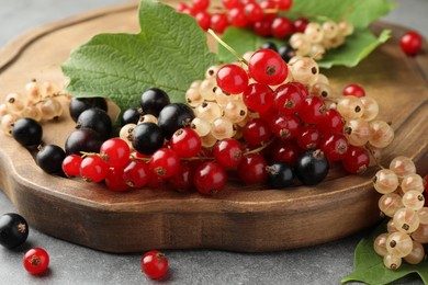 Different fresh ripe currants and green leaves on table, closeup
