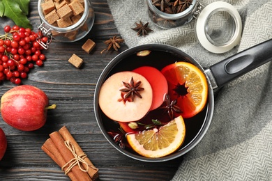 Photo of Saucepan with tasty mulled wine on black wooden table, flat lay