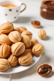 Photo of Homemade walnut shaped cookies with boiled condensed milk on white table, closeup