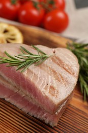 Pieces of delicious tuna steak with rosemary on wooden board, closeup