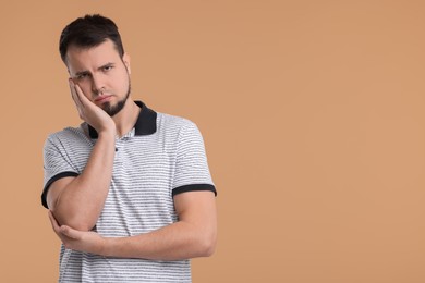 Portrait of sad man on beige background, space for text