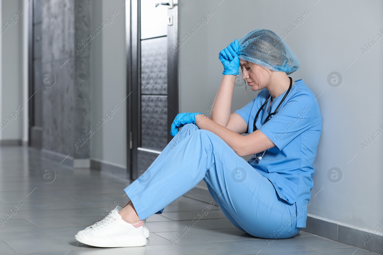 Photo of Exhausted doctor sitting on floor in hospital