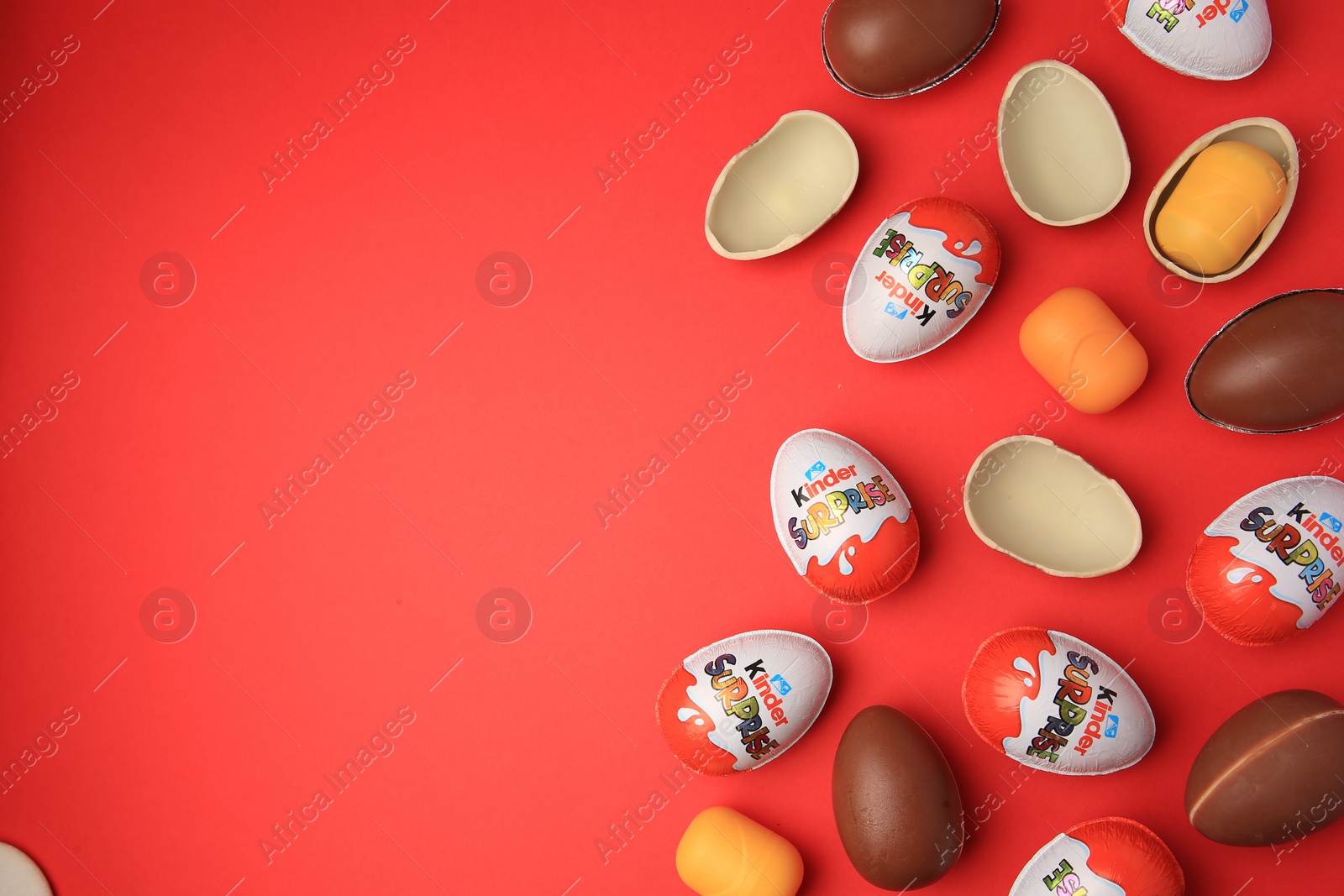 Photo of Sveti Vlas, Bulgaria - June 29, 2023: Kinder Surprise Eggs and plastic capsules on red background, flat lay. Space for text