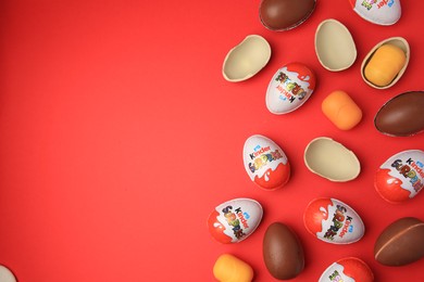 Sveti Vlas, Bulgaria - June 29, 2023: Kinder Surprise Eggs and plastic capsules on red background, flat lay. Space for text