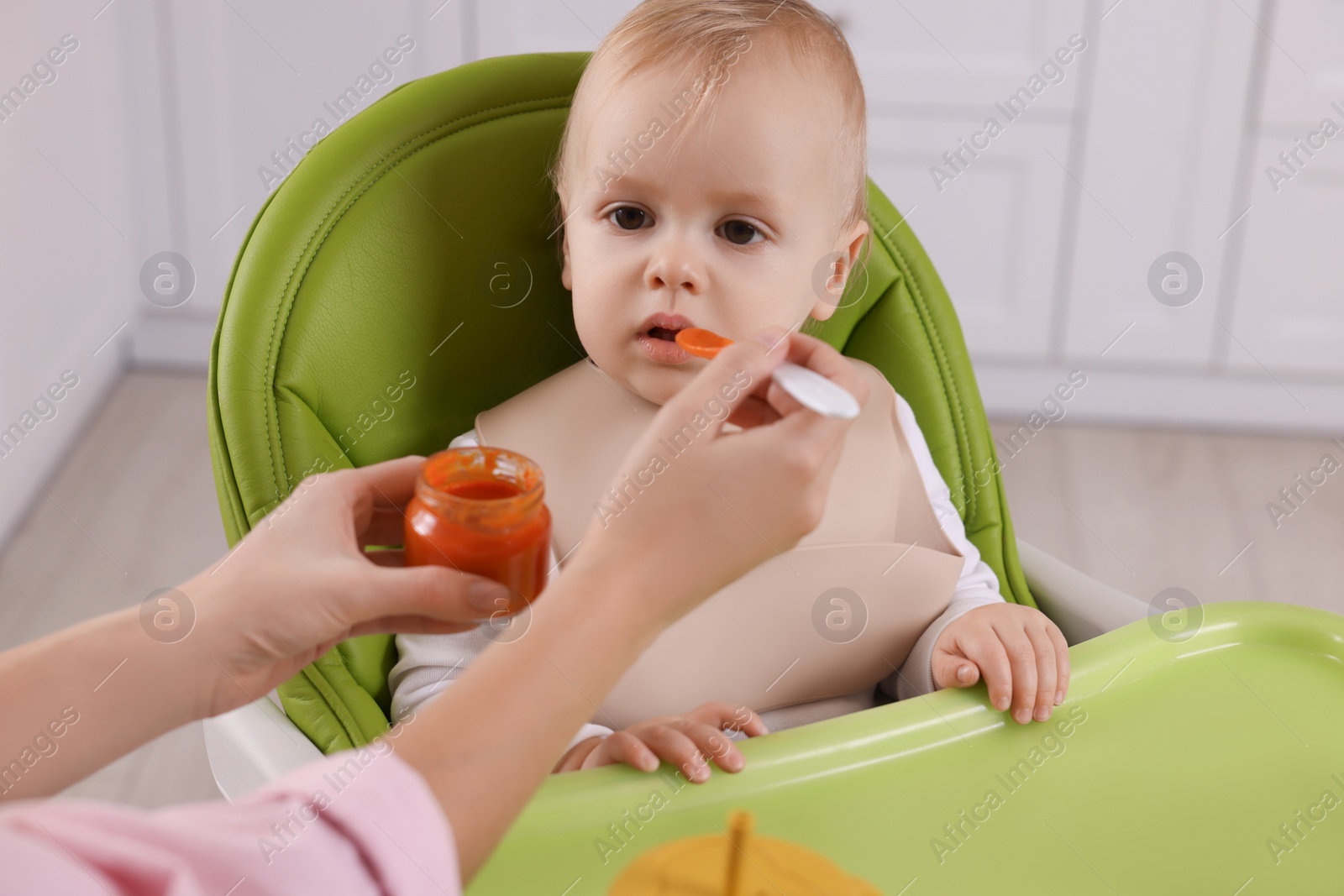 Photo of Mother feeding her cute little baby with healthy food at home