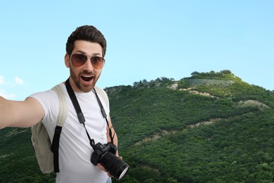 Smiling man with camera taking selfie in mountains