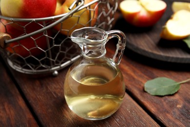 Photo of Natural apple vinegar and fresh fruits on wooden table