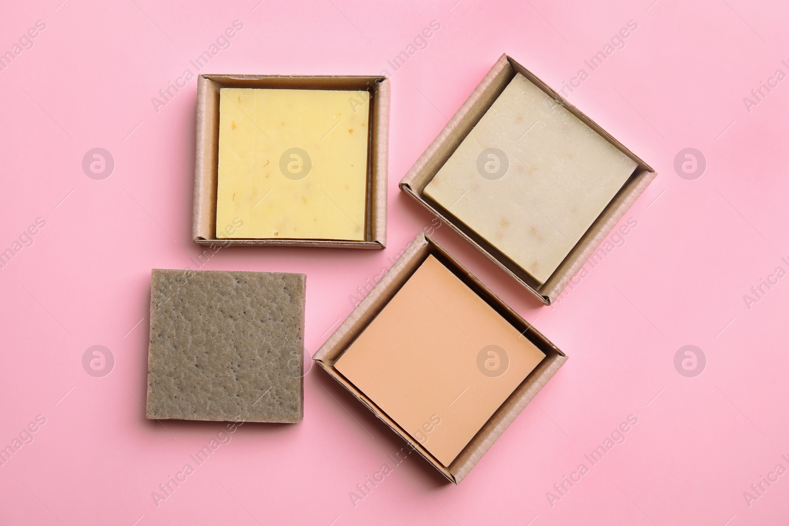Photo of Hand made soap bars in cardboard packages on color background, top view