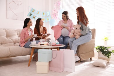 Photo of Happy pregnant woman spending time with friends at baby shower party