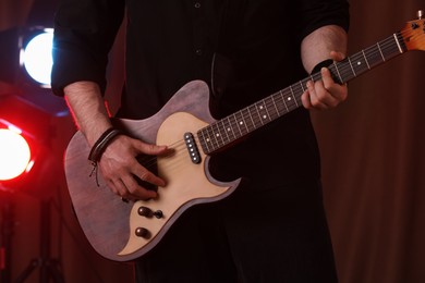 Photo of Man playing electric guitar on stage, closeup. Rock music