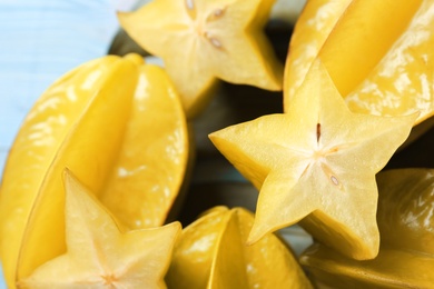 Photo of Delicious carambola fruits on light blue table, closeup