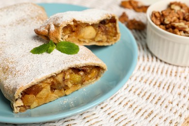 Delicious strudel with apples, nuts and raisins on wicker mat, closeup