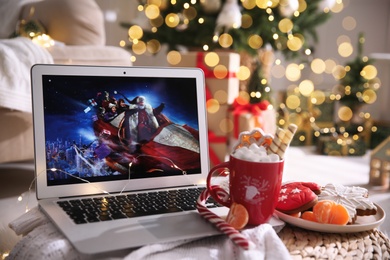 Photo of MYKOLAIV, UKRAINE - DECEMBER 25, 2020: Laptop displaying Christmas Chronicles movie at home. Cozy winter holidays atmosphere